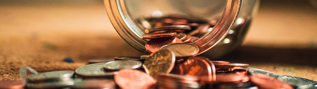 A jar with coins spilling onto a table