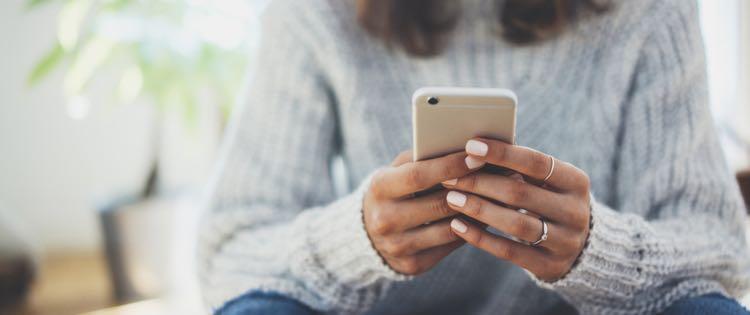 close up of woman holding phone in both hands 