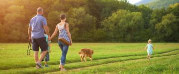 Family with two kids and dog walking through field