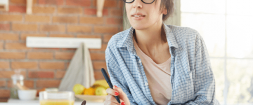 Photo of a dark haired woman using a day planner in her kitchen