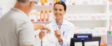 Photo of young female pharmacist handing a bag to an older man